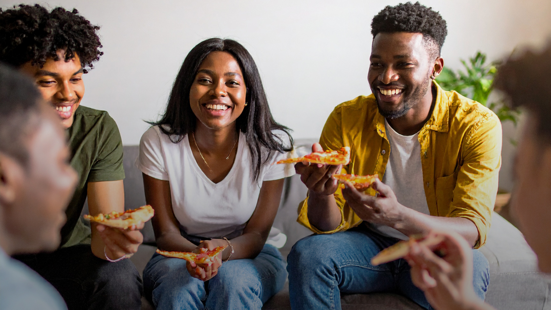 4 étudiants souriants autour d'une part de pizza