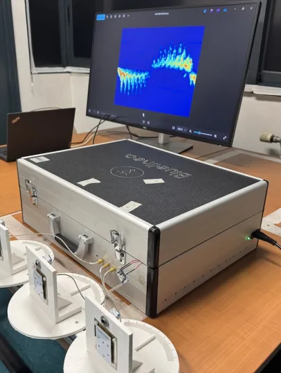 Photo du dispositif de détection de mouvement par radar : sur une table sont posés des capteurs et une valise de matériel reliés à un ordinateur