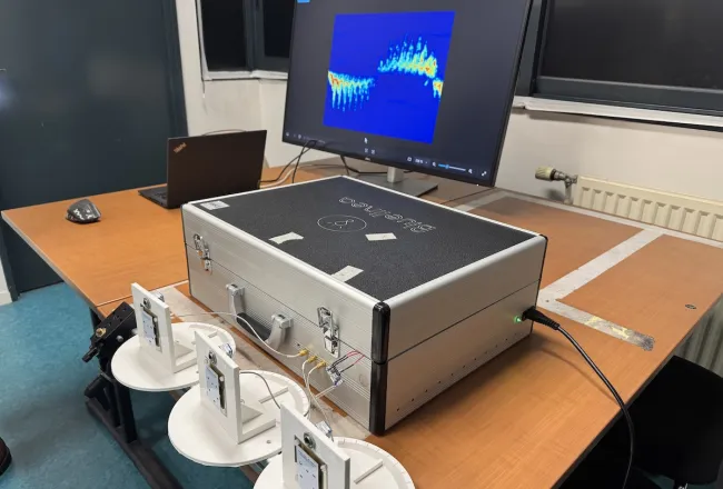Photo du dispositif de détection de mouvement par radar : sur une table sont posés des capteurs et une valise de matériel reliés à un ordinateur
