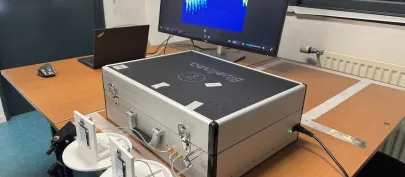 Photo du dispositif de détection de mouvement par radar : sur une table sont posés des capteurs et une valise de matériel reliés à un ordinateur